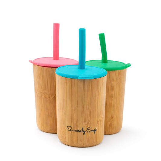 Three bamboo cups with colorful lids and straws on a white background