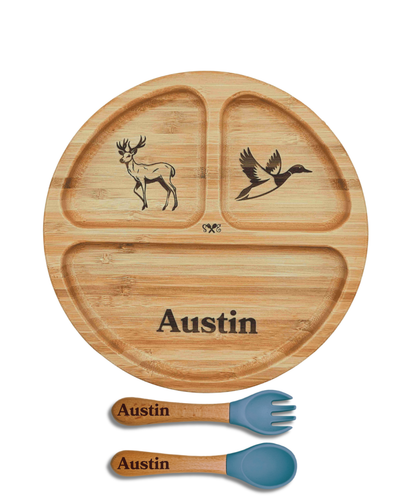 A round bamboo divided baby plate with three sections, engraved with a deer, a duck, and the name 'Austin', shown with two matching bamboo utensils (a fork and a spoon) with blue silicone tips on a white background.